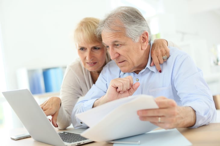 Senior couple studying retirement tax information online