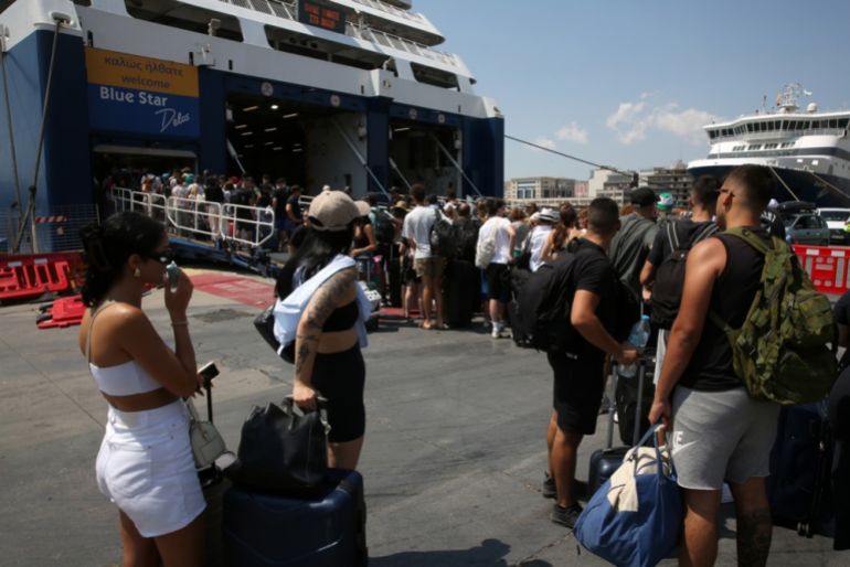Călători așteptând să se îmbarce pe un feribot, portul Piraeus, Grecia, 8 august 2025