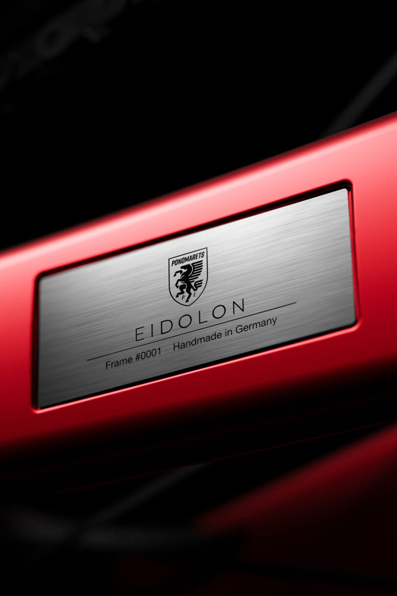 Close-up of a nameplate on a red surface, labeled "Eidolon," with a logo and text "Frame #0001 Handmade in Germany.
