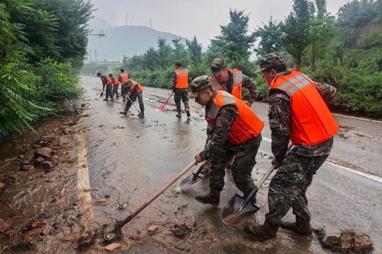Forțe ale Poliției Populare Armate chineze curăță aluviuni pe un drum în districtul Miyun, nordul Beijingului, 27 iulie 2025 (Wang Xiqing/Xinhua via AP)